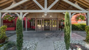 A building with a wooden facade, a covered entrance, and hanging flower baskets.