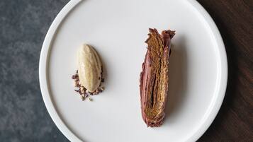 Un plato blanco ovalado con un postre sobre una mesa de madera oscura.