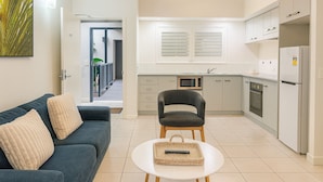 A compact living space with a kitchenette, a sofa, a dining table, and a chair. - Blue Lagoon Resort (Trinity Beach)