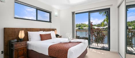 A modern hotel room with a large bed, a nightstand, a lamp, and a ceiling fan.