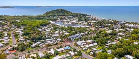 An aerial view of a coastal residential area with houses, roads, and a small body of water.
