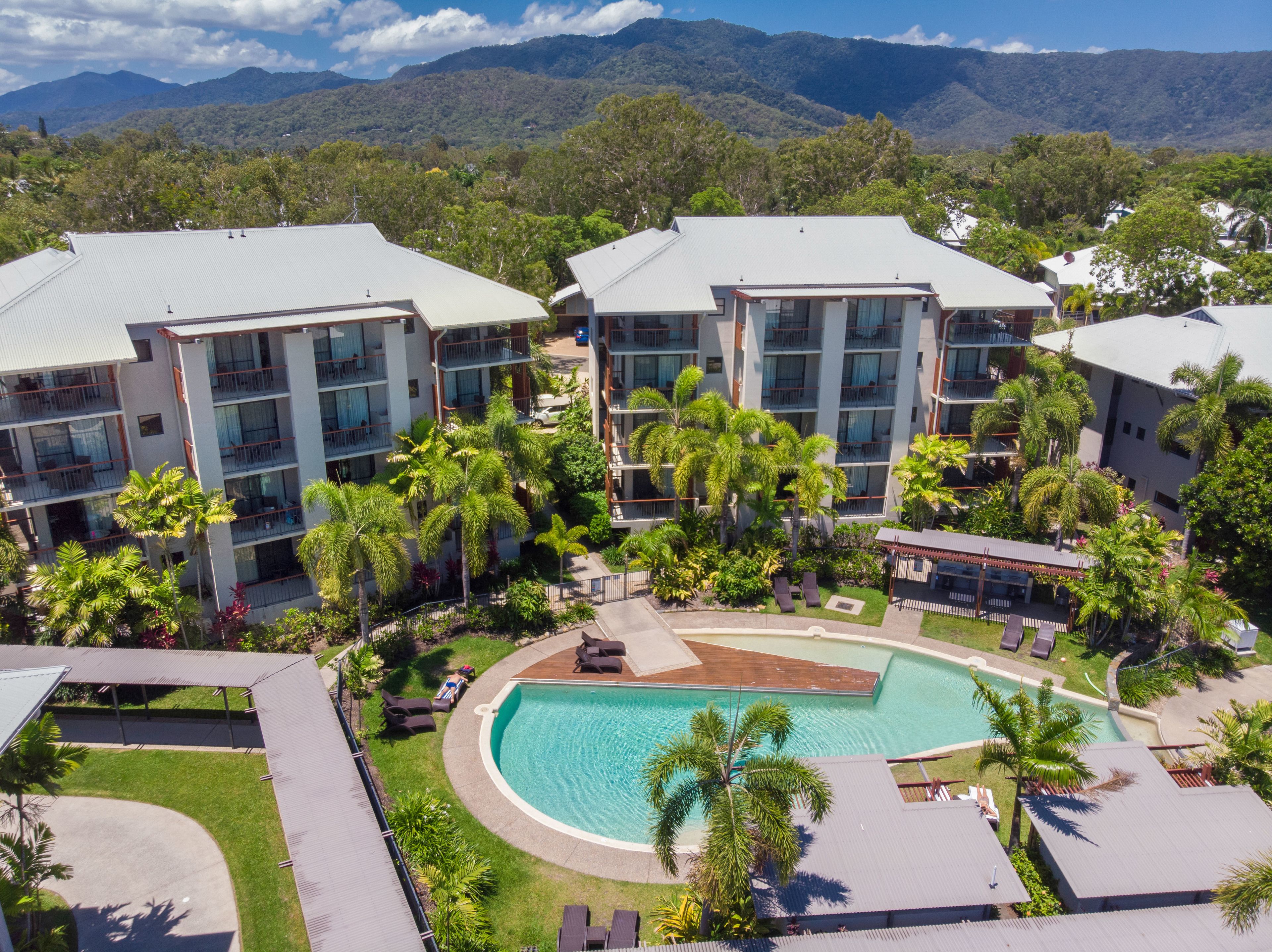 Un resort con edificios de varios pisos, una piscina y abundante vegetación.