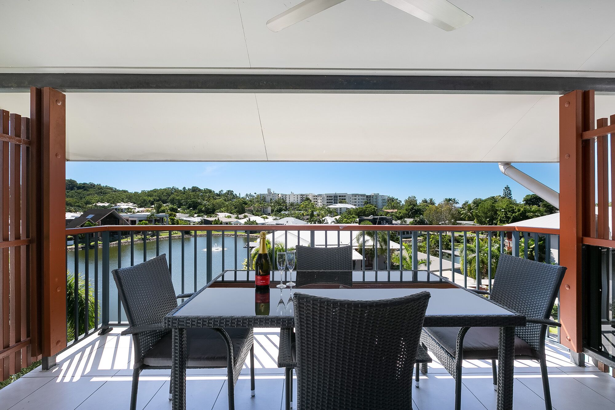 Een balkon met een tafel en stoelen, met uitzicht op water en gebouwen.