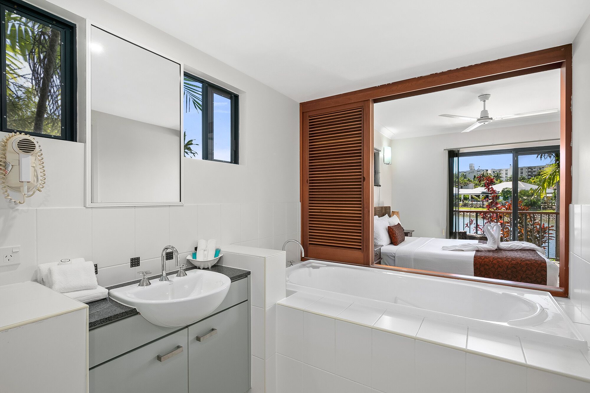 A modern bathroom with a large mirror, a sink, and a bathtub.