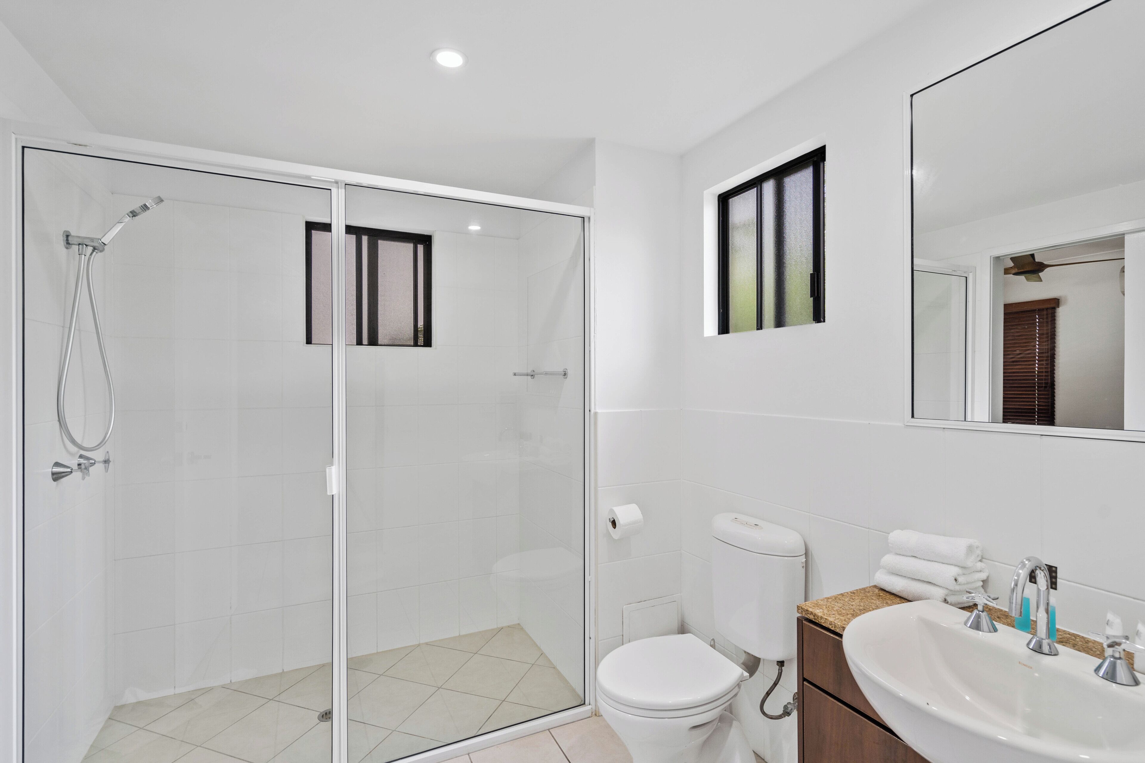 Une salle de bain moderne dotée d’une douche à parois de verre, de toilettes et d’un lavabo avec un plan de travail.