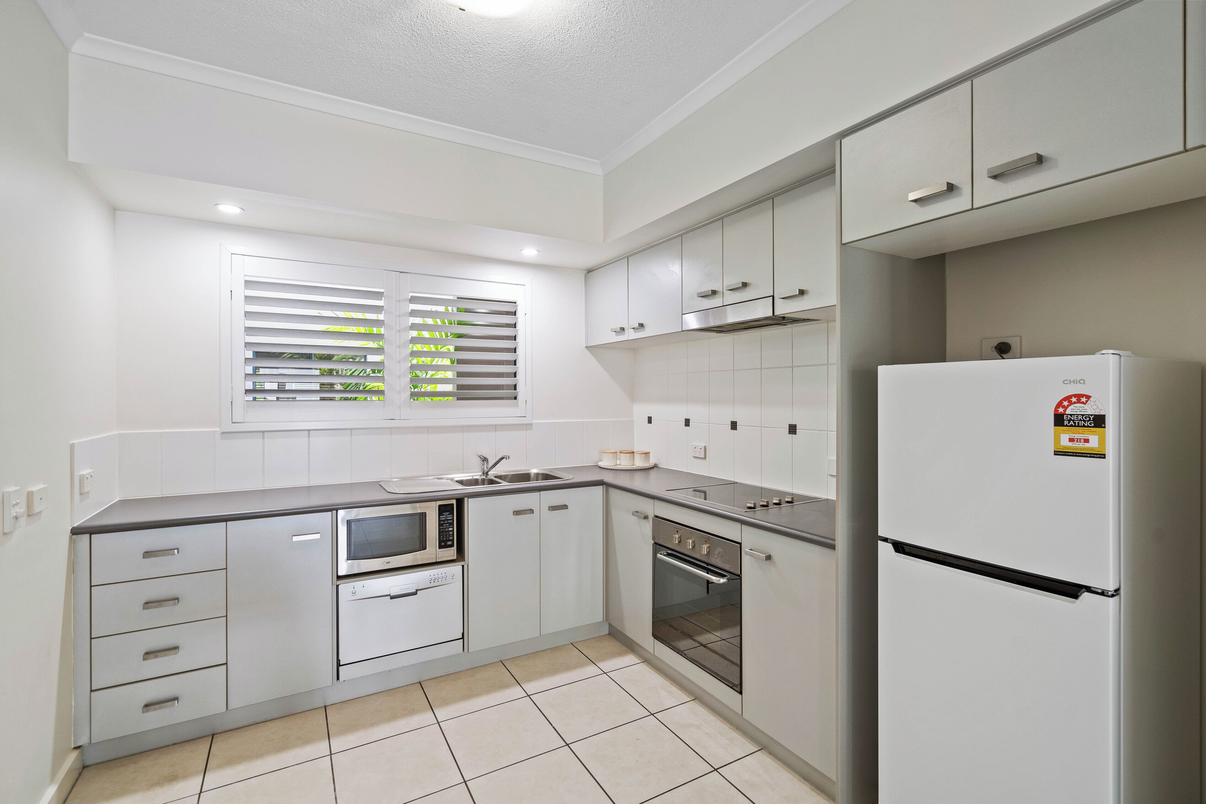 A modern kitchen with white cabinets, a built-in microwave, oven, and refrigerator.