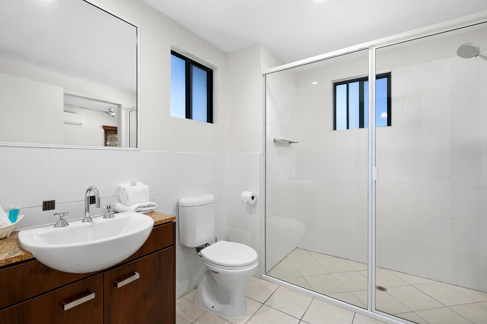 Une salle de bain moderne avec une douche à parois de verre, un lavabo blanc et des toilettes.
