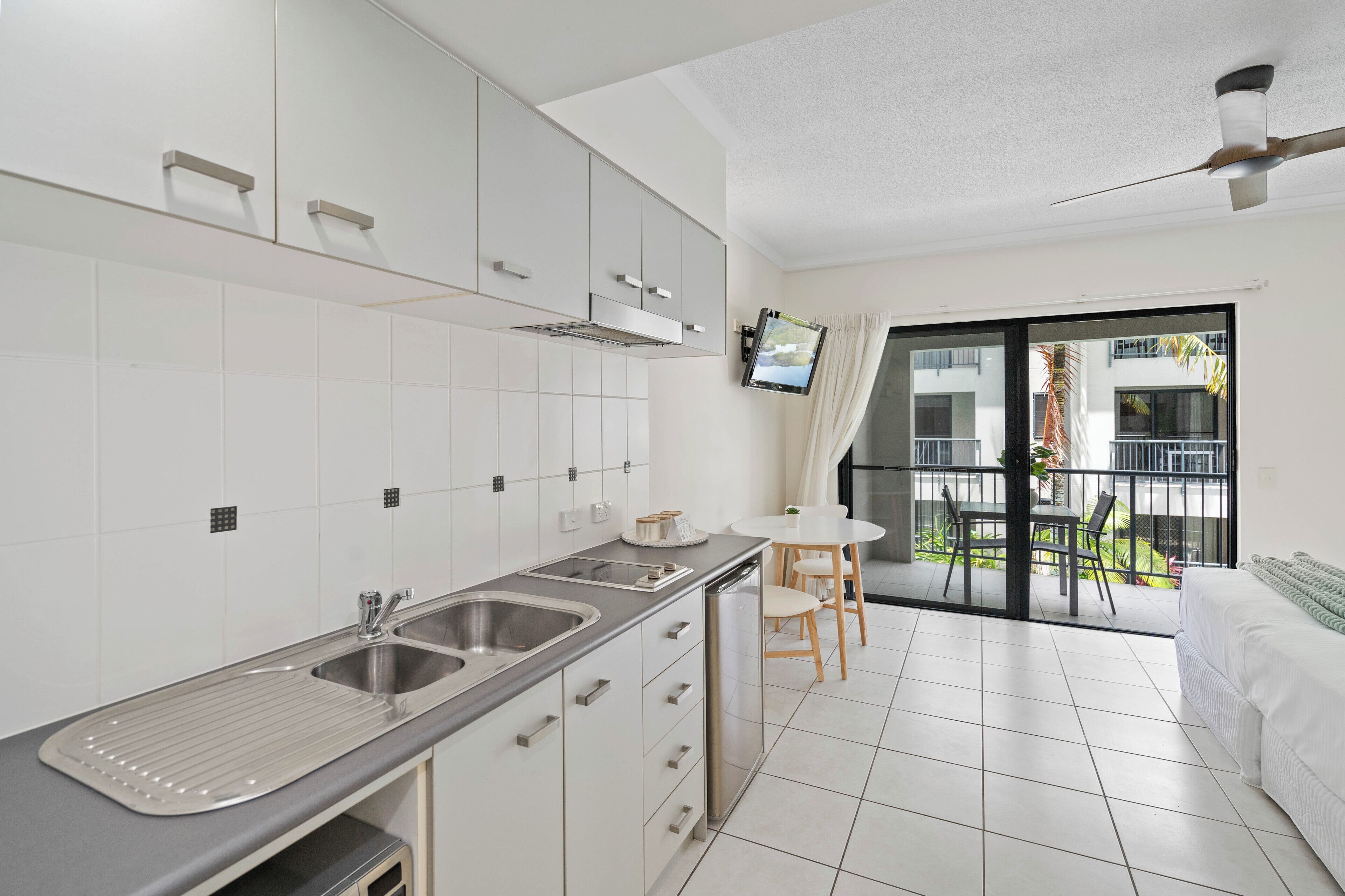 Una cucina moderna con lavastoviglie integrata, un'area pranzo con tavolo e sedie, e un balcone con vista sul panorama circostante.