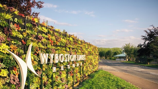A sign for Wybo Stanley Resort with a lush vertical garden backdrop. - Drift Inn at Wyboston Lakes (Bedford)