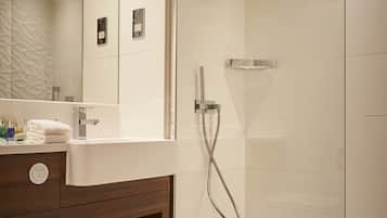 A modern bathroom with a glass-enclosed shower, a white toilet, and a vanity with a mirror.