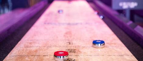A shuffleboard table with numbered ends and a score display in the background.