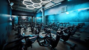 A gym with multiple exercise bikes, mirrors, and a hexagonal light fixture on the ceiling. - Drift Inn at Wyboston Lakes (Bedford)