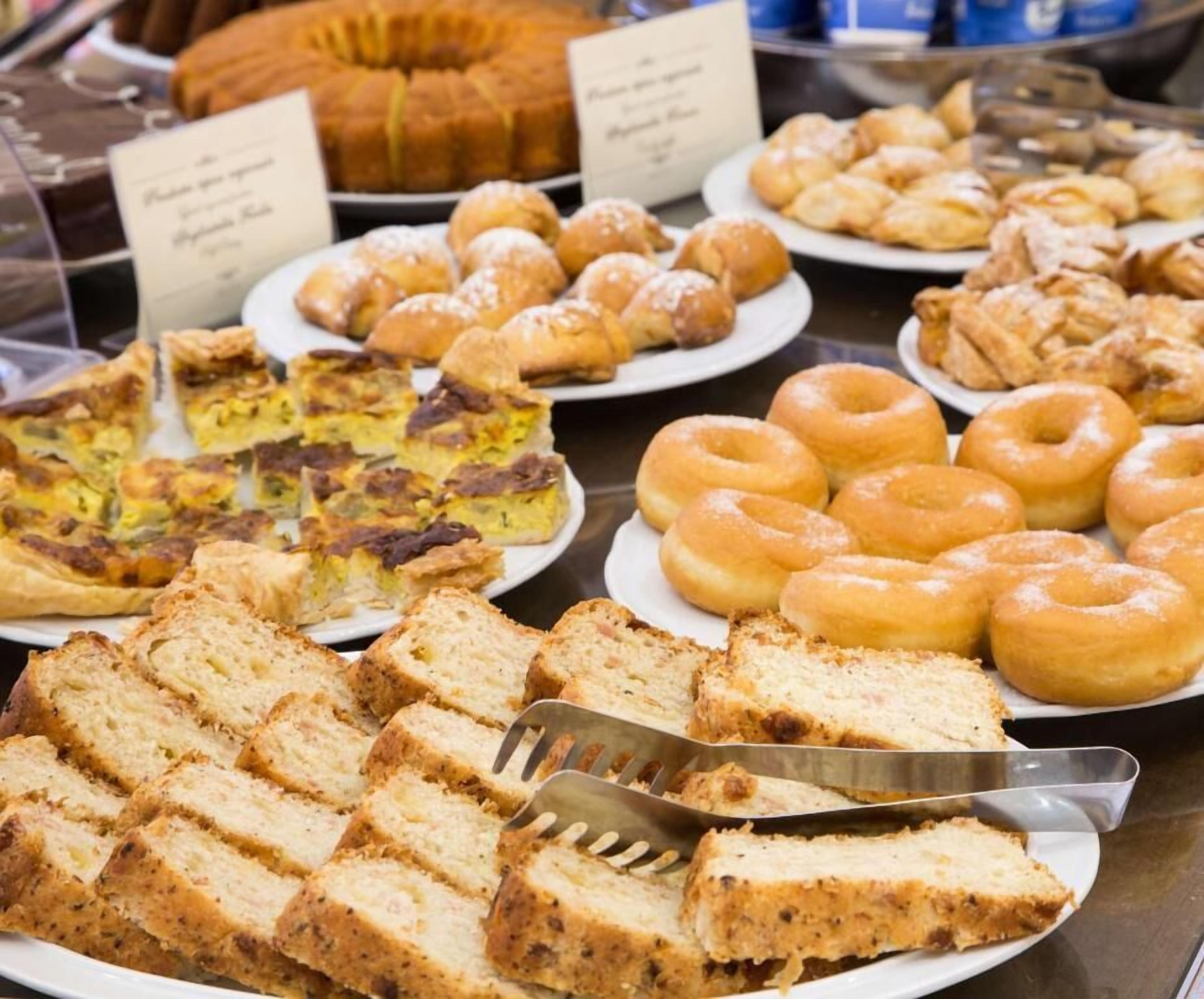A buffet with various baked goods including bread, pastries, and a quiche.