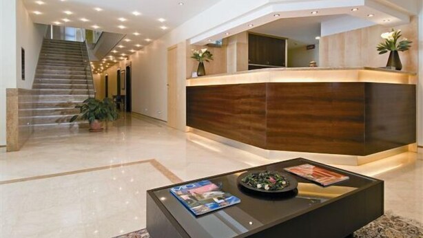 Un moderno vestíbulo de hotel con mostrador de recepción, una escalera y una mesa de centro con revistas.
