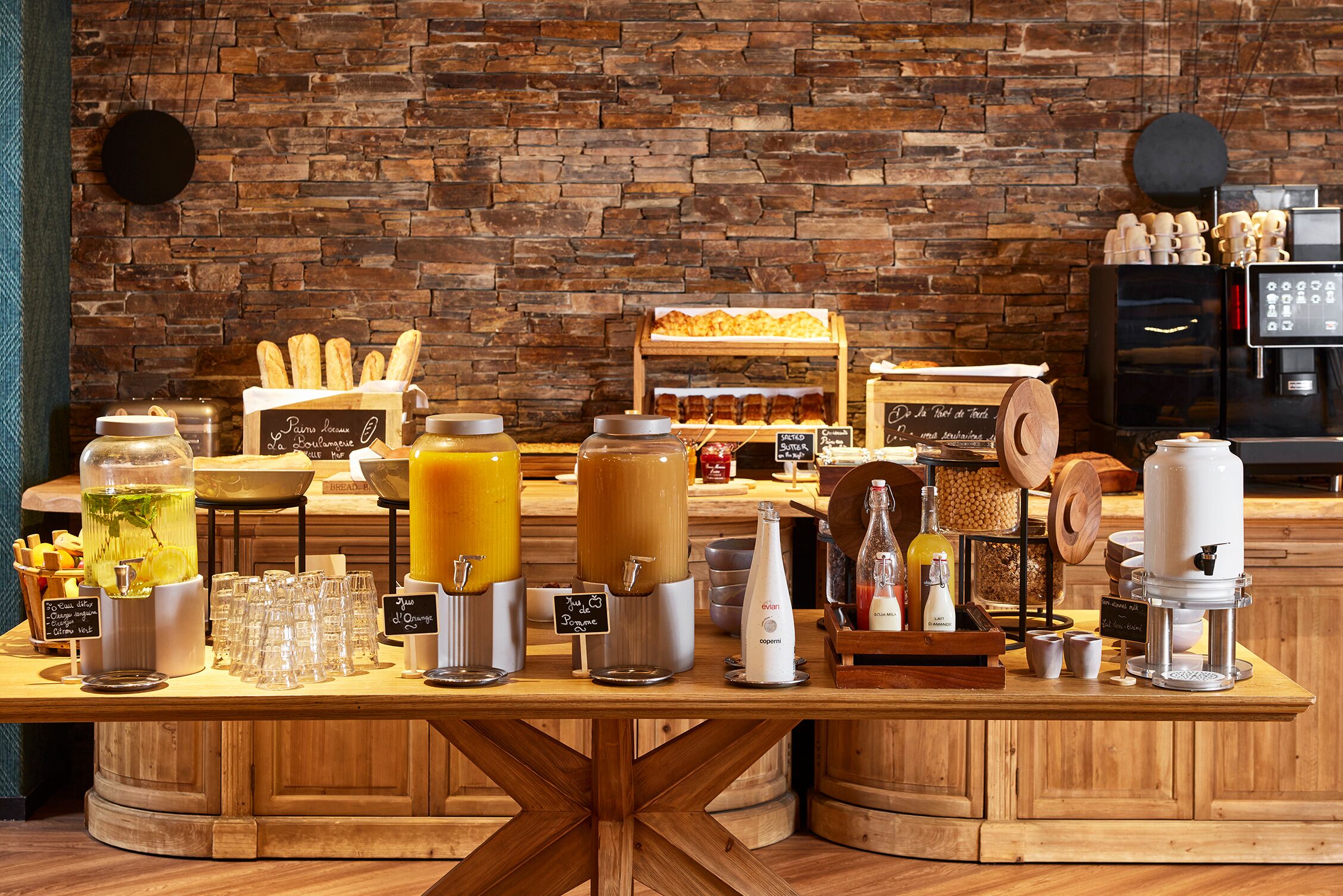 A breakfast bar with various food and drink options, including bread, pastries, and coffee machines.