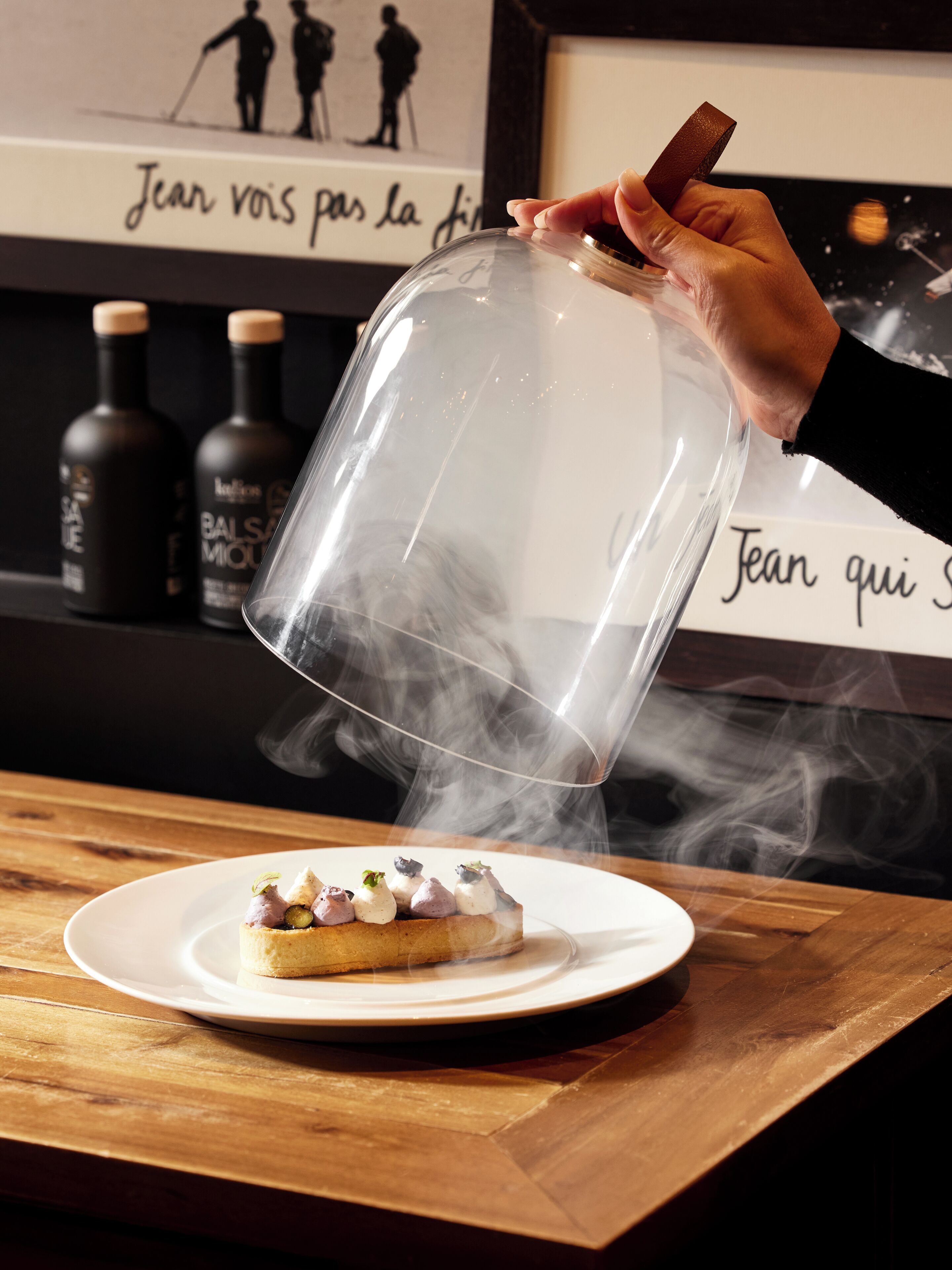 Una mano vertiendo humo sobre un postre en un plato.
