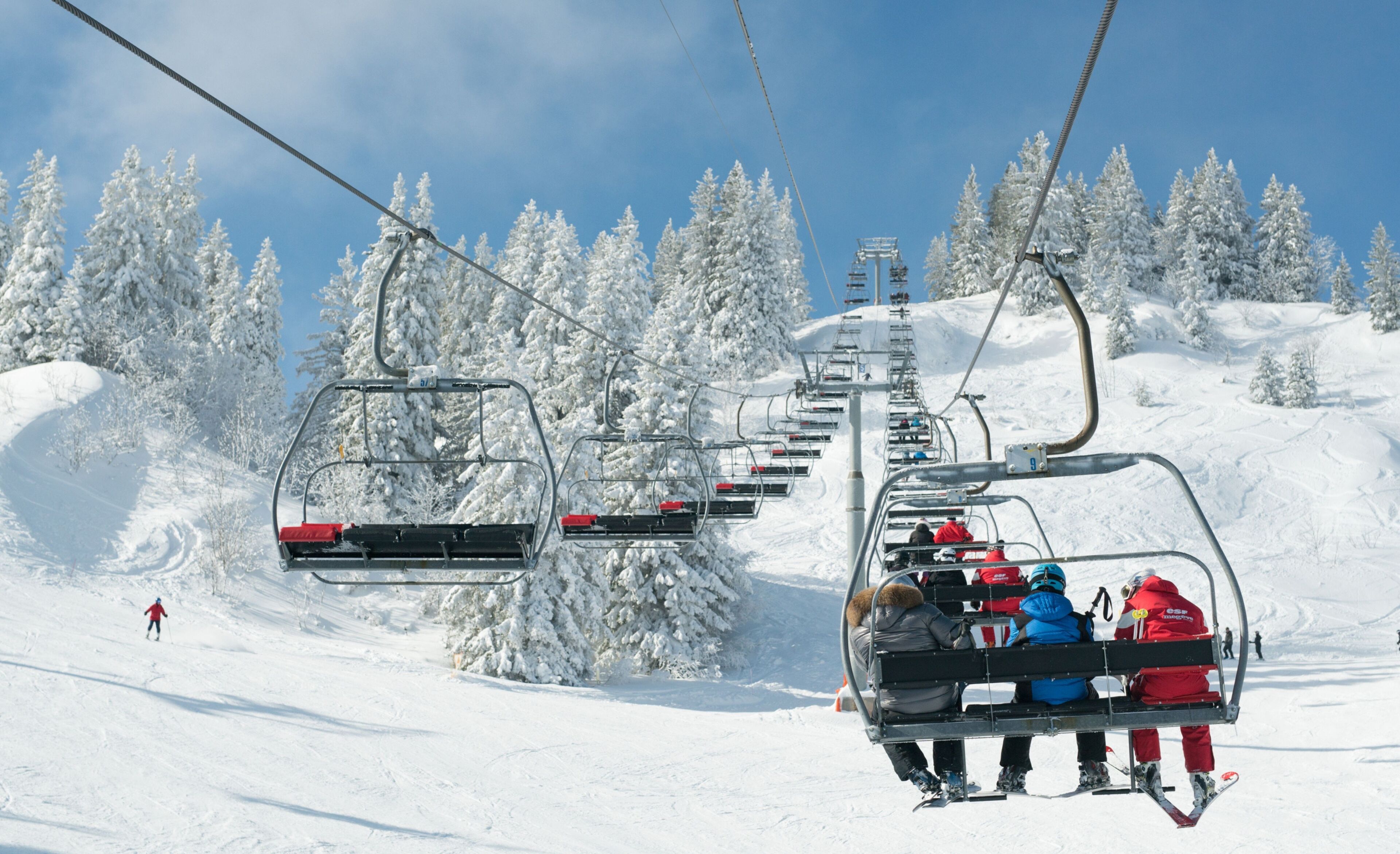 Gondola de esqui com passageiros subindo uma encosta coberta de neve.