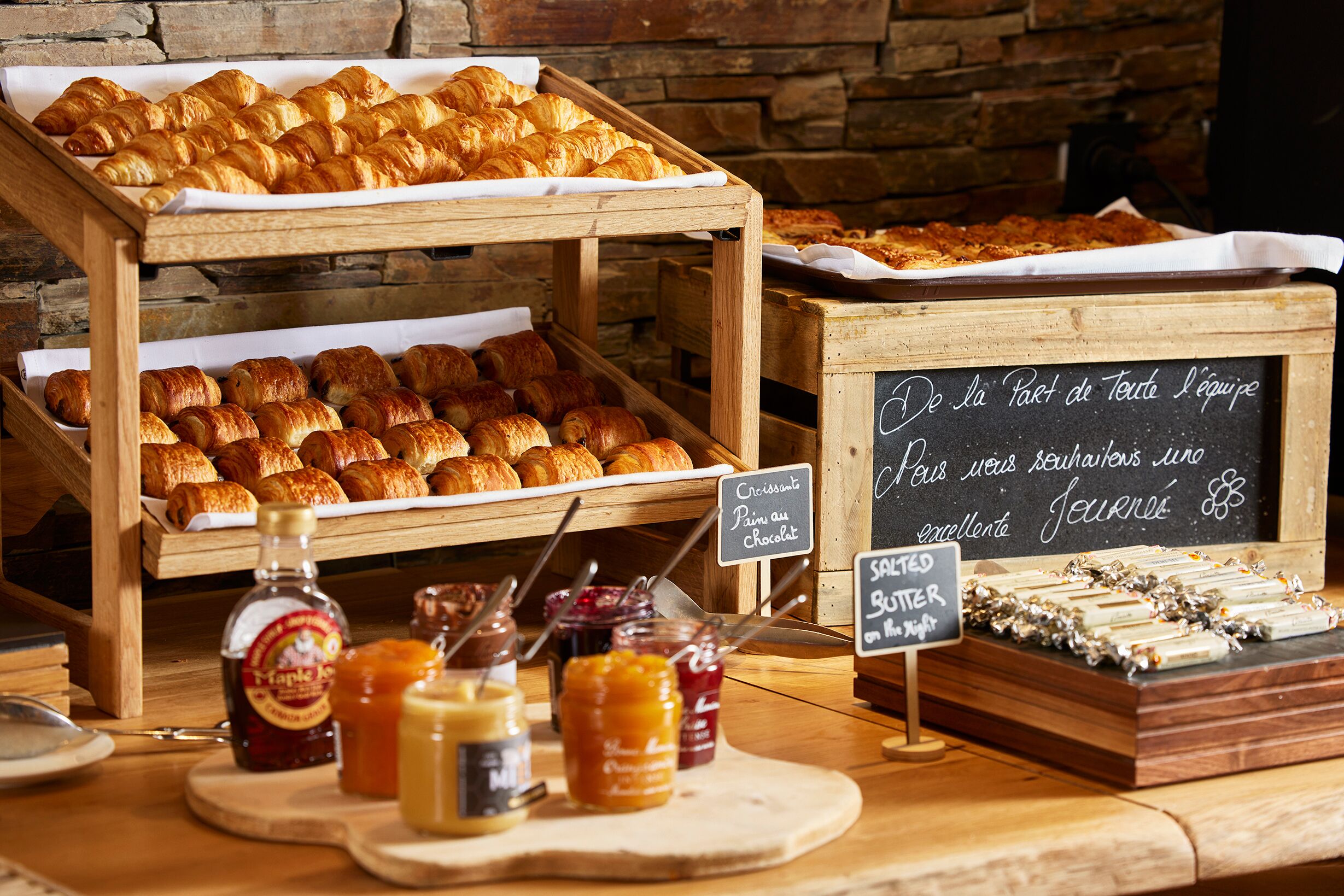 A bakery display with pastries, jams, and a chalkboard sign.