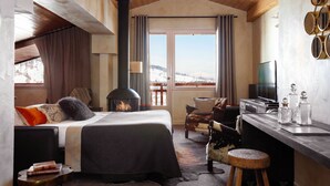 Um quarto aconchegante com uma cama, lareira, escrivaninha e vista para o exterior.