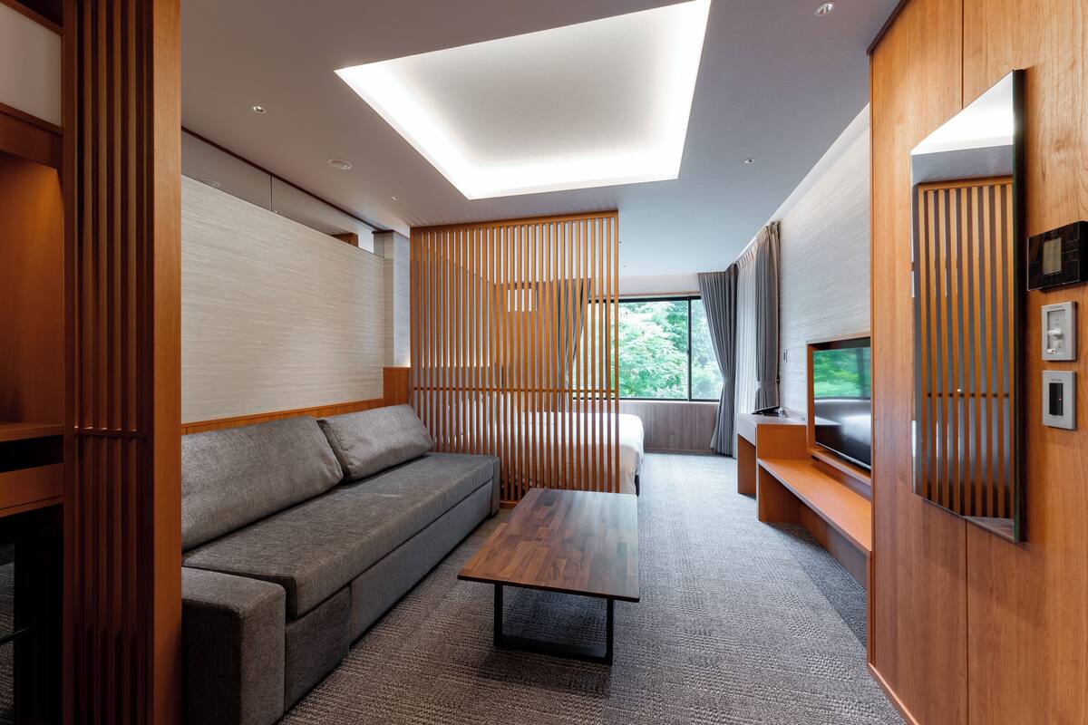A modern interior with a sofa, a coffee table, a TV, and a large window.