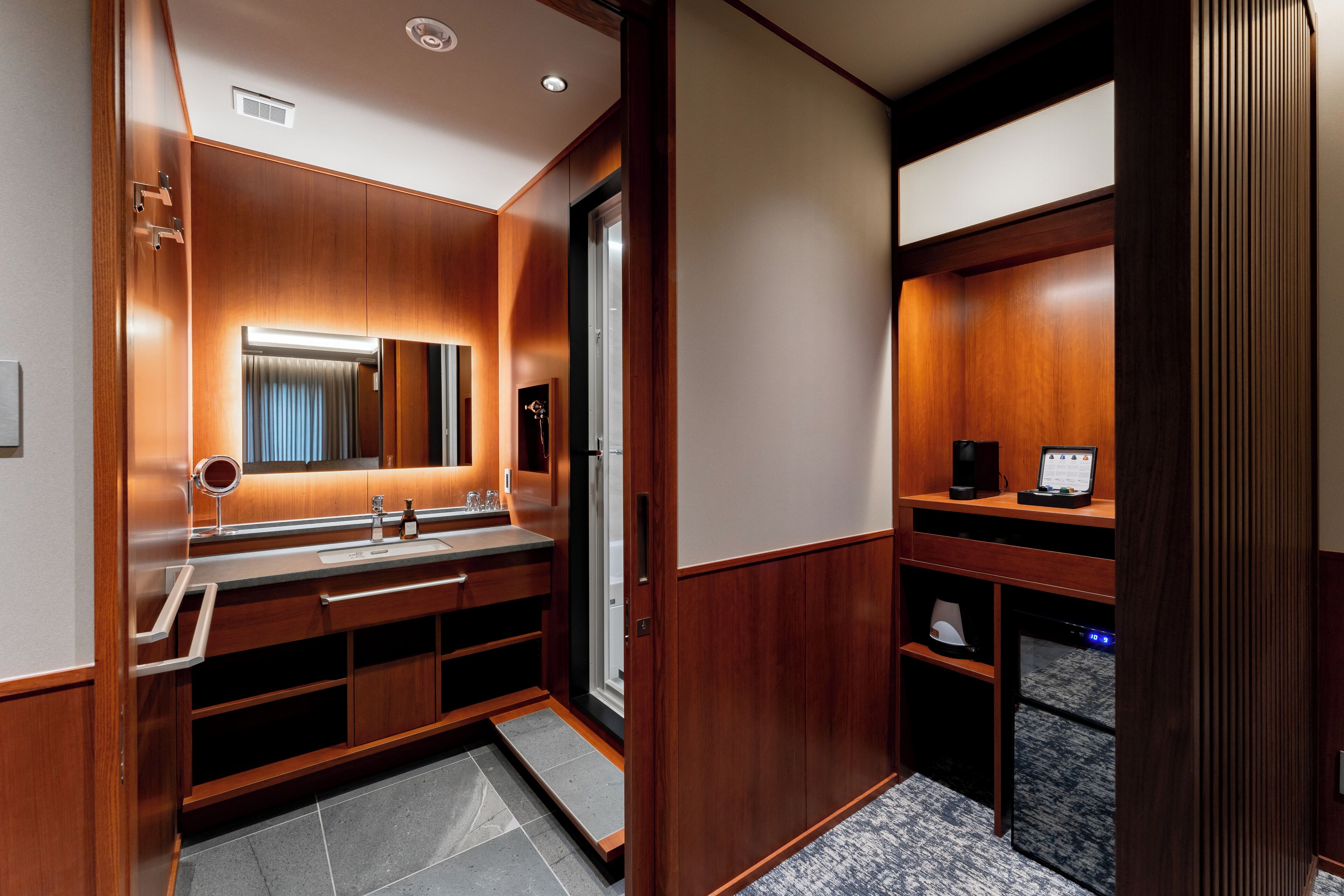 A modern bathroom with a wooden vanity, a large mirror, and a built-in shower.