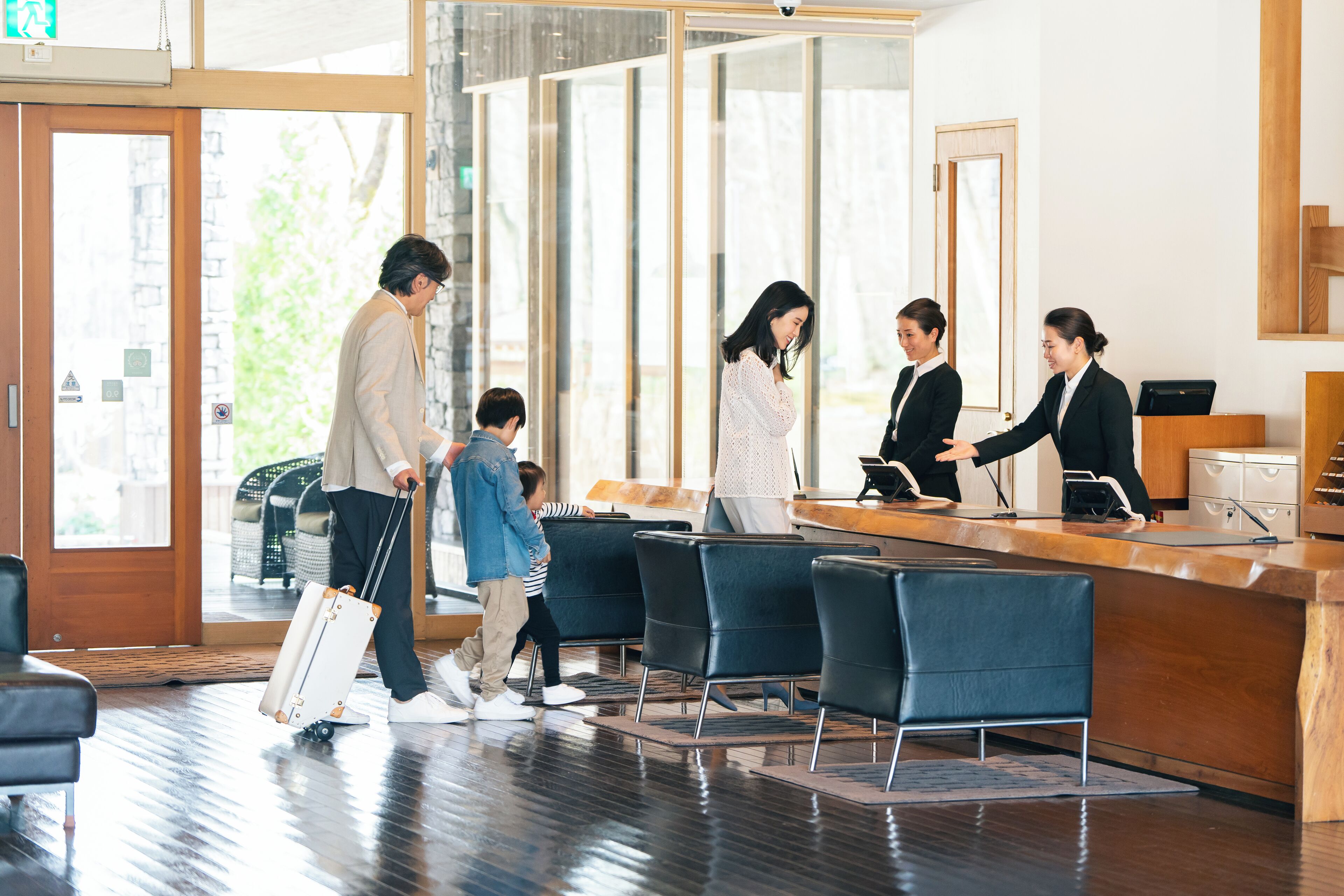 A reception area with a wooden reception desk, black chairs, and a glass door leading outside.