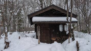 Una cabaña de madera con techo nevado, rodeada de árboles cubiertos de nieve.