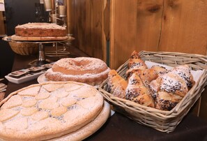 Variedad de productos horneados, incluyendo un pastel, una tarta y pasteles, sobre una mesa de madera.