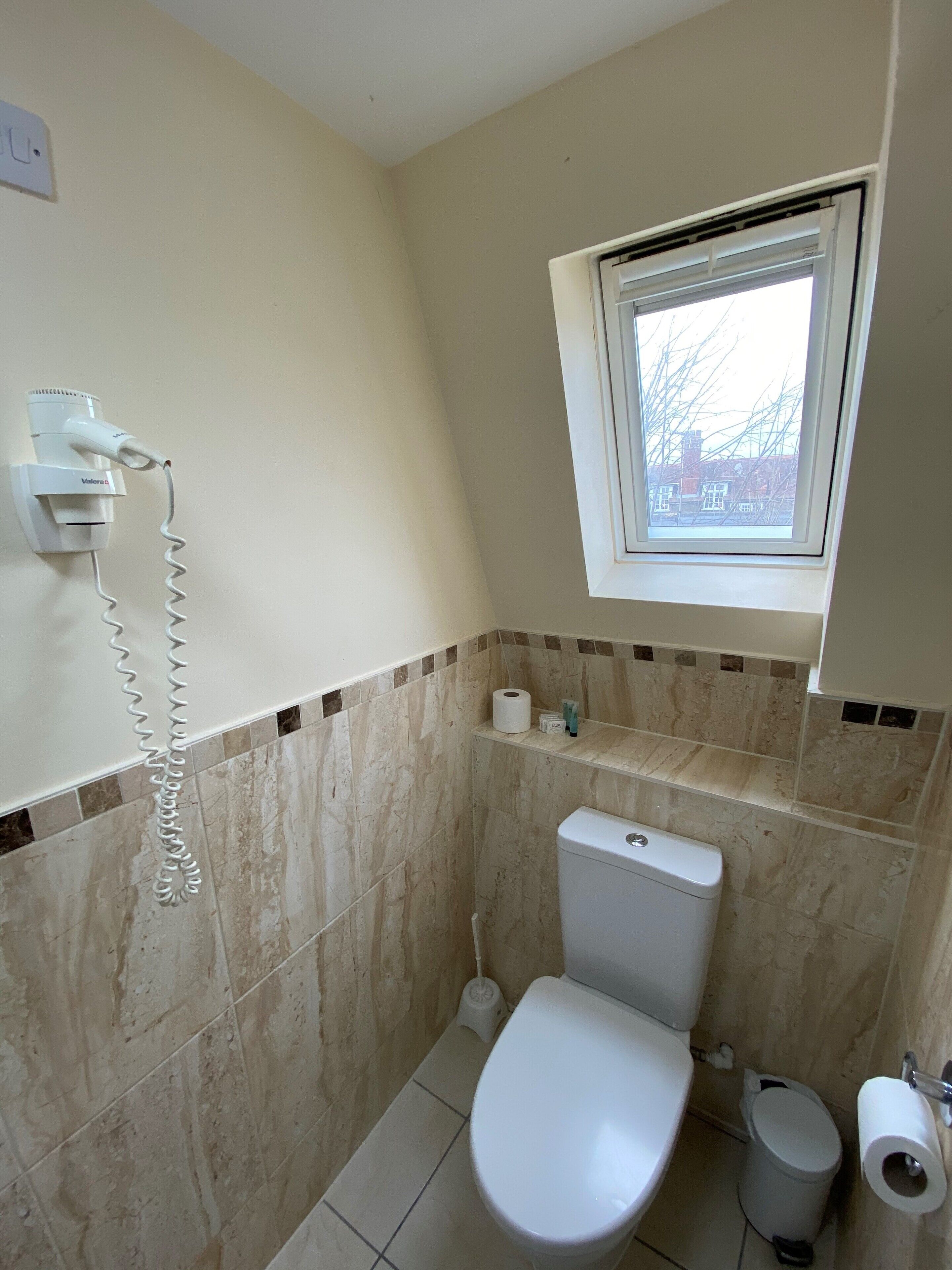 Un baño pequeño con inodoro, bidé, toallero y ventana.