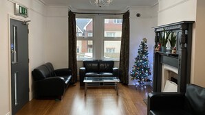 Uma sala de estar com lareira, árvore de Natal, sofás de couro e vista para o exterior através de grandes janelas.