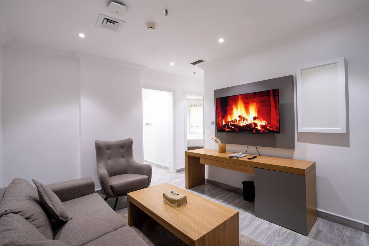 A modern living room with a sofa, armchair, coffee table, TV, and a fireplace.