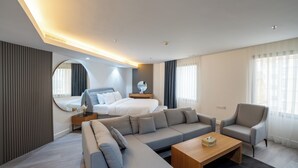 Une chambre d’hôtel moderne avec un grand lit, un canapé, un fauteuil et une petite table.