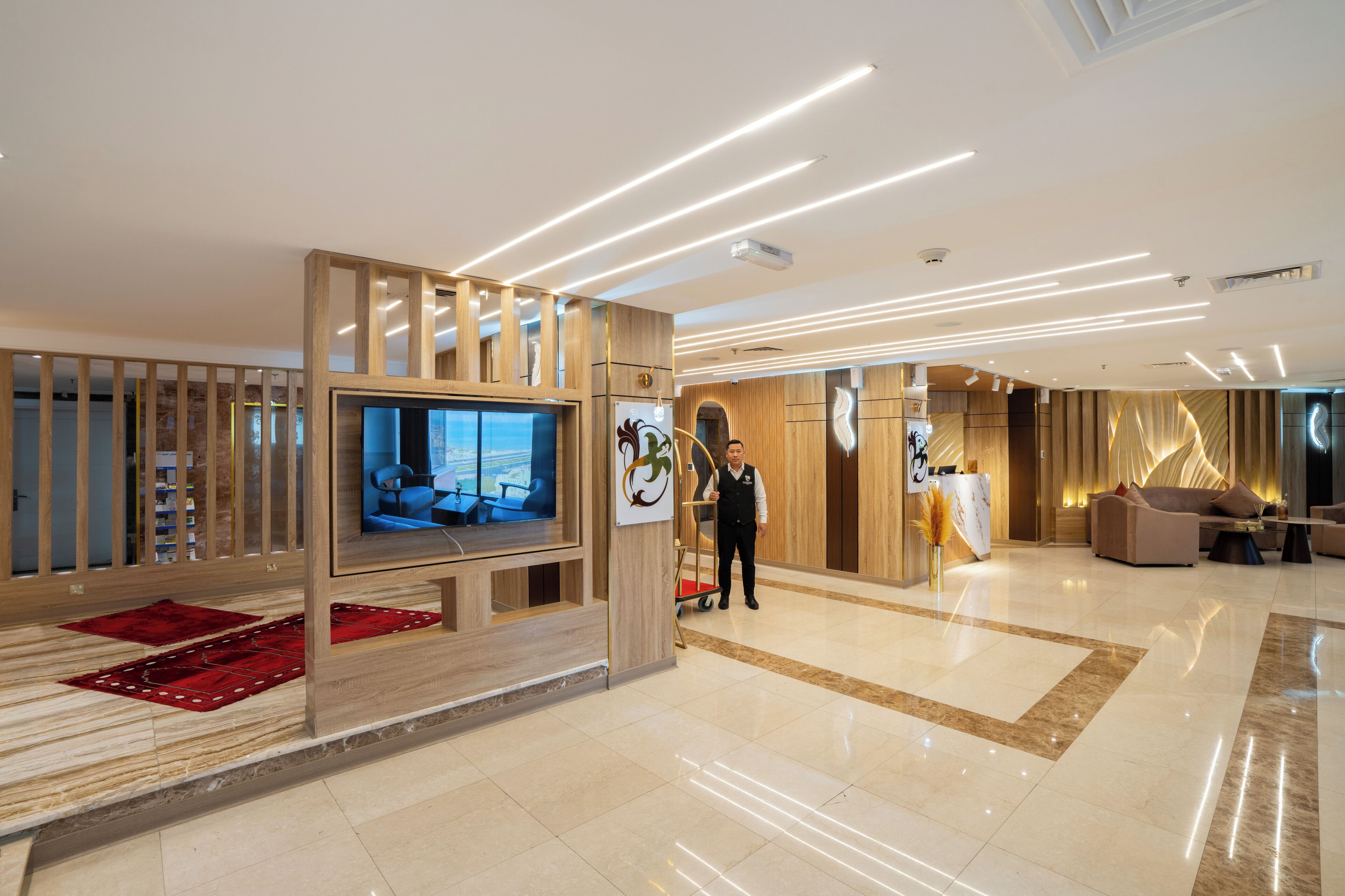 A modern lobby with a reception desk, a television screen, and a clean, polished floor.