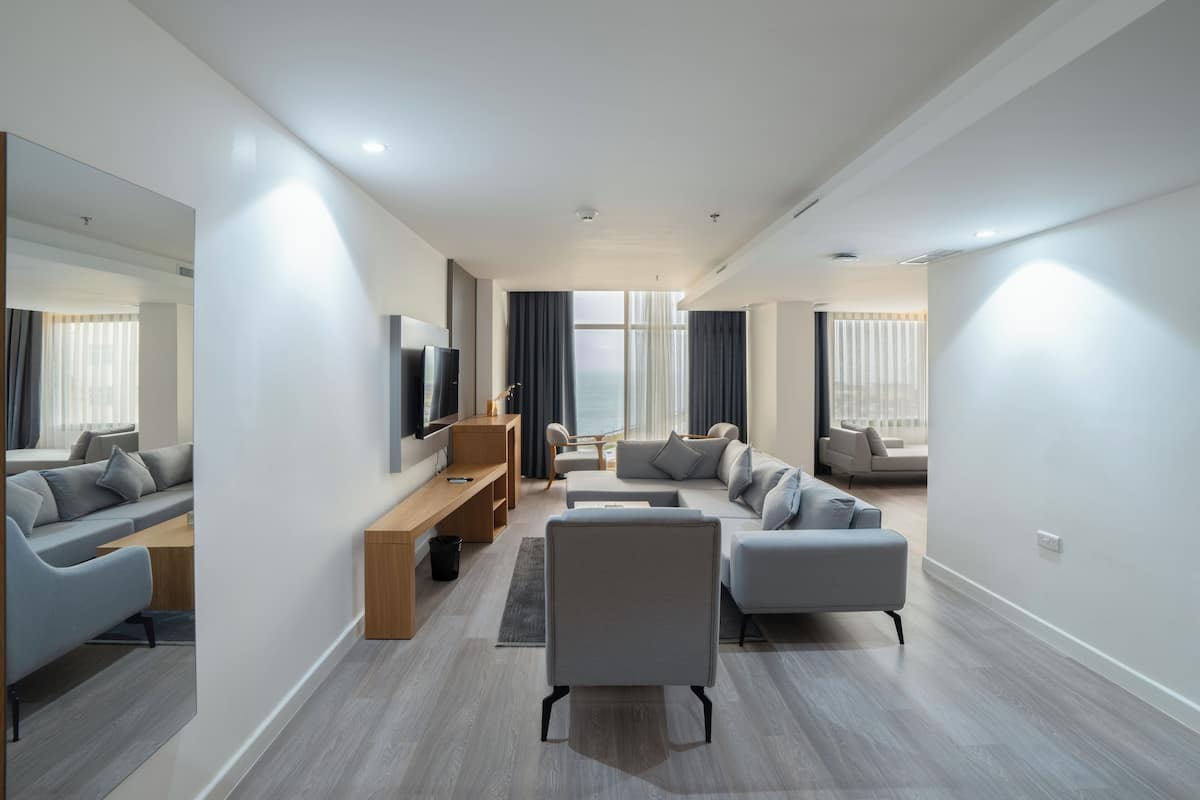 A modern living room with a sofa, a coffee table, a TV, and a large window with curtains.