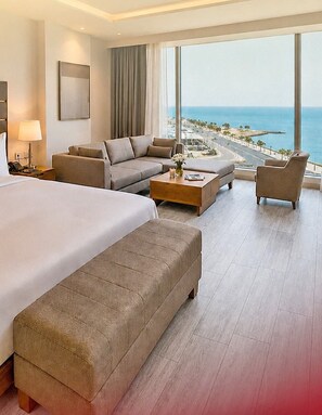 Ein Hotelzimmer mit einem großen Bett, einer Couch, einem Couchtisch und Meerblick.