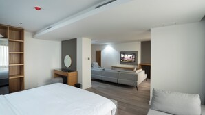 Une chambre d’hôtel moderne équipée d’un grand lit, d’un canapé, d’une télévision et d’un bureau avec un miroir.