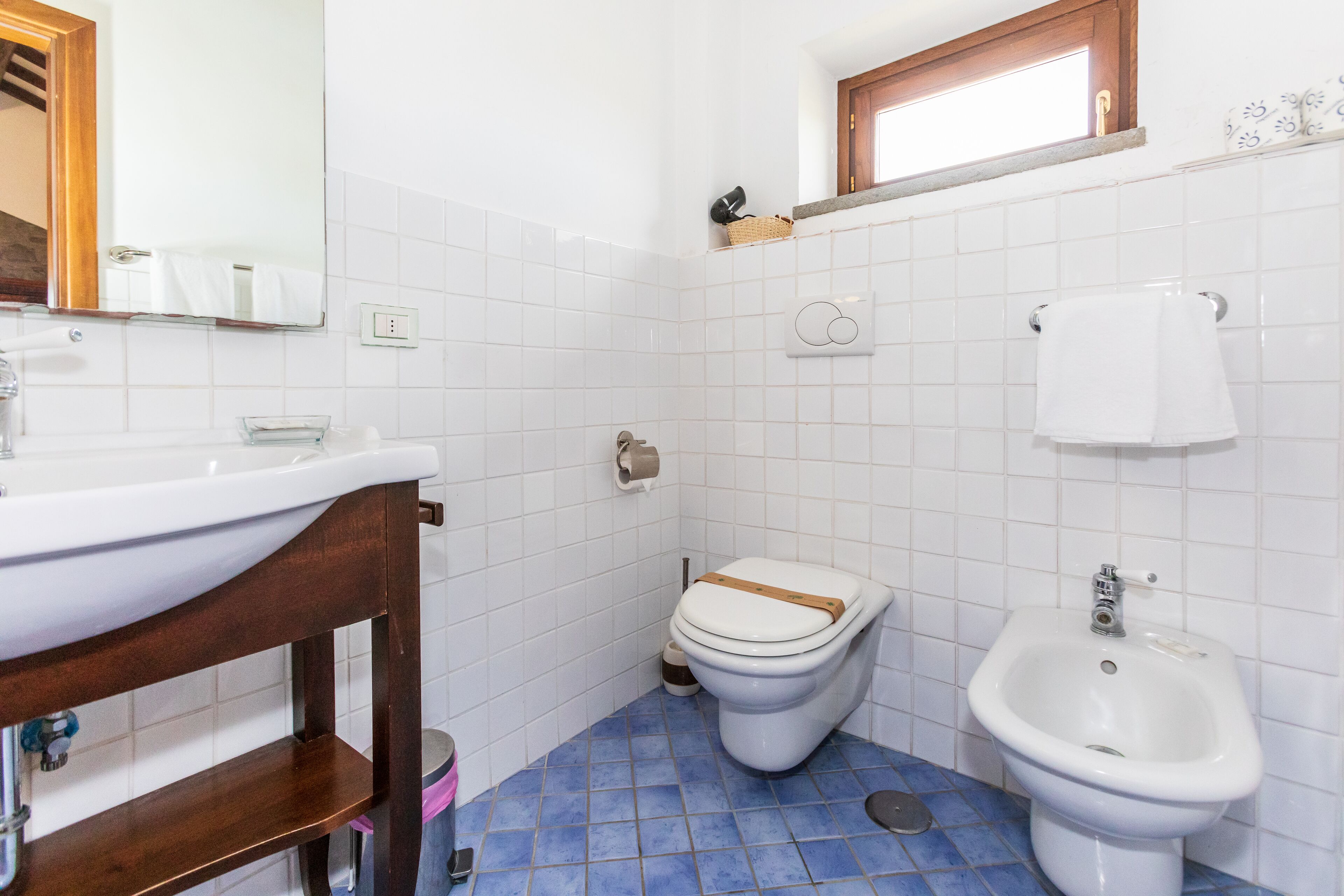 A bathroom with a white sink, a toilet, and a bidet.