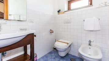 A bathroom with a white sink, a toilet, and a bidet.