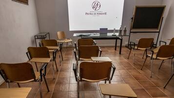 Un aula con filas de pupitres y sillas, una pantalla de proyector y una pizarra.