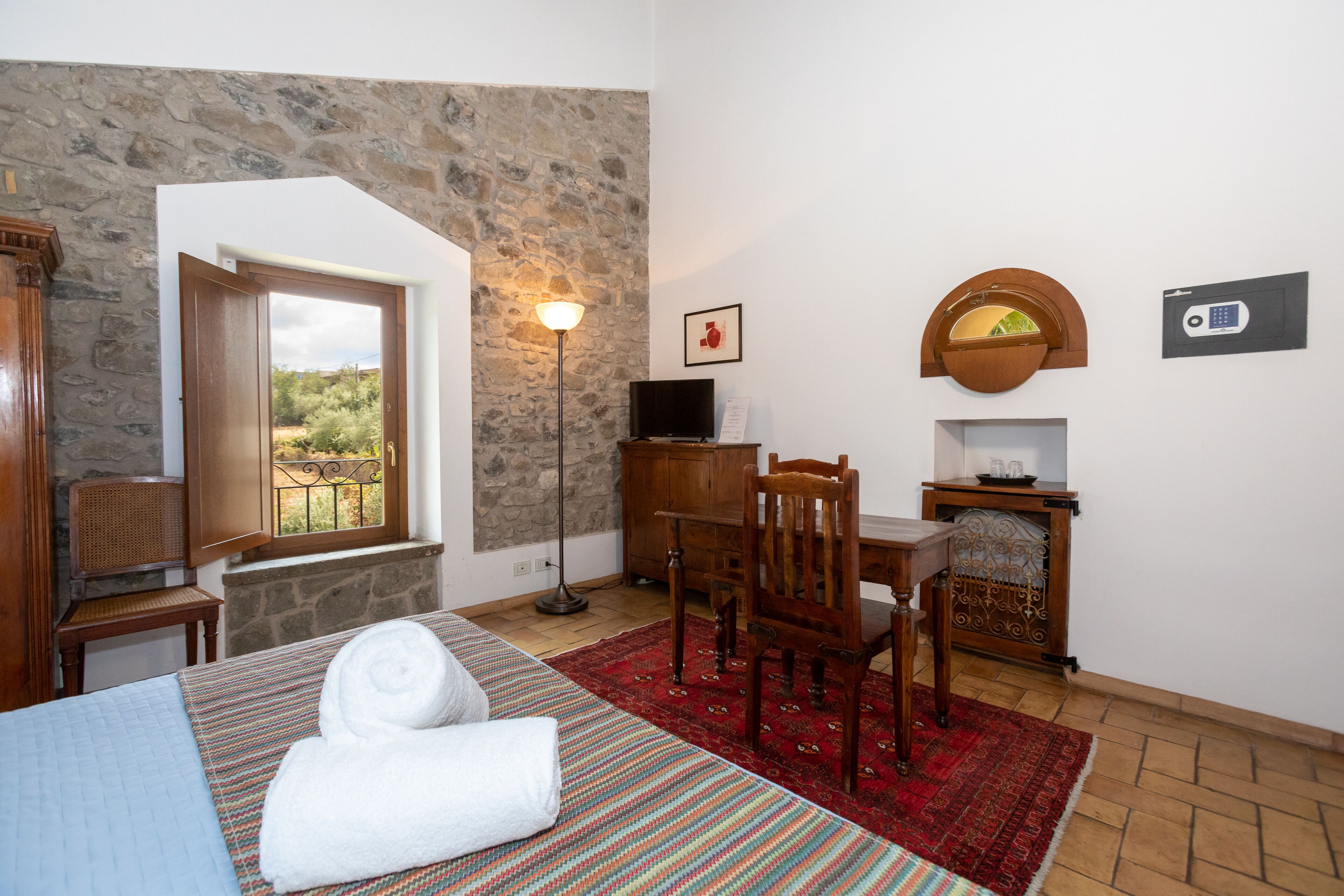 Ein Hotelzimmer mit Bett, Schreibtisch, Stuhl, Fernseher, Lampe und Blick ins Freie.