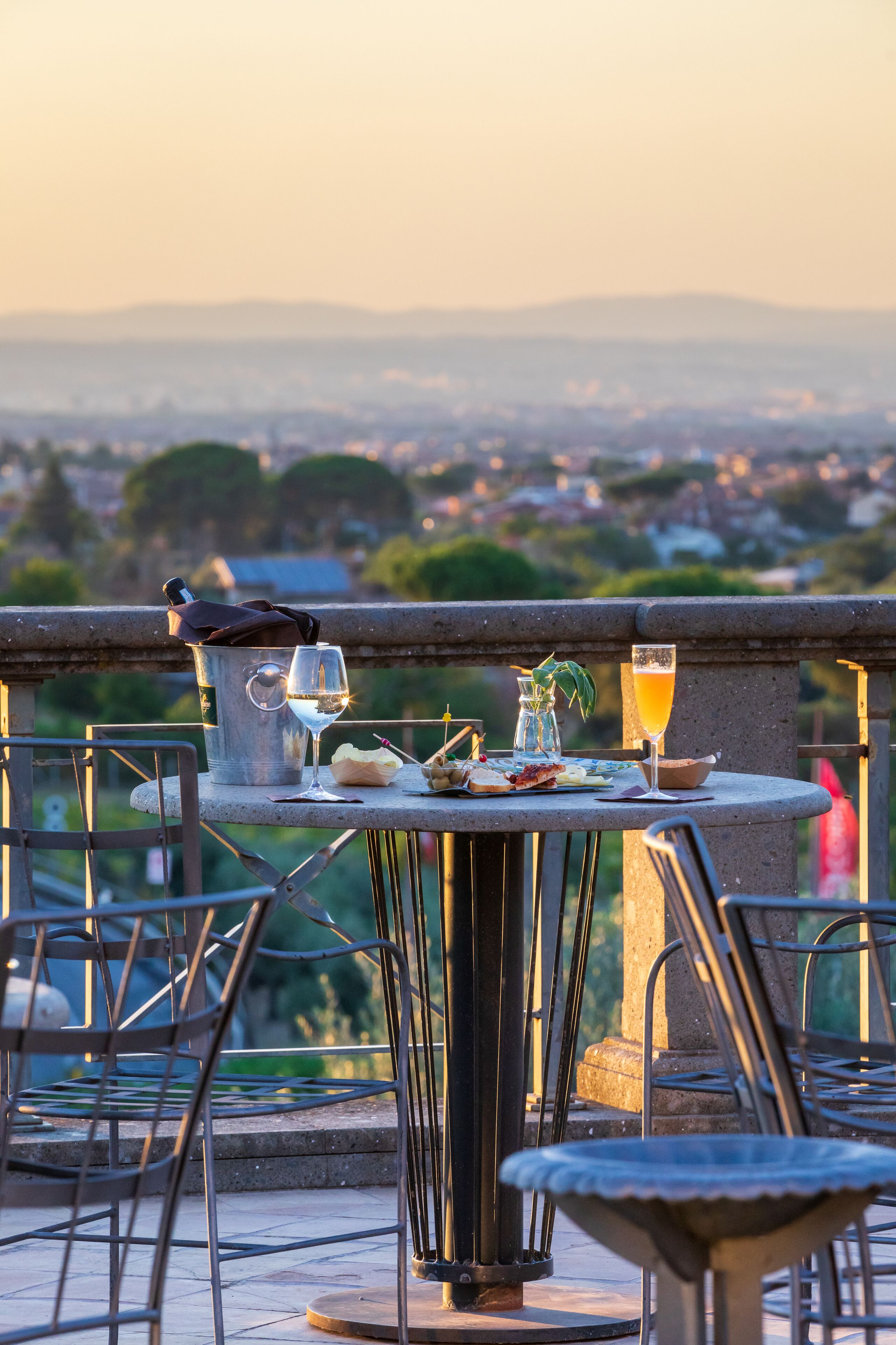 En terrasse med et spisebord, komplet med vinglas, en flaske og et glas appelsinjuice.