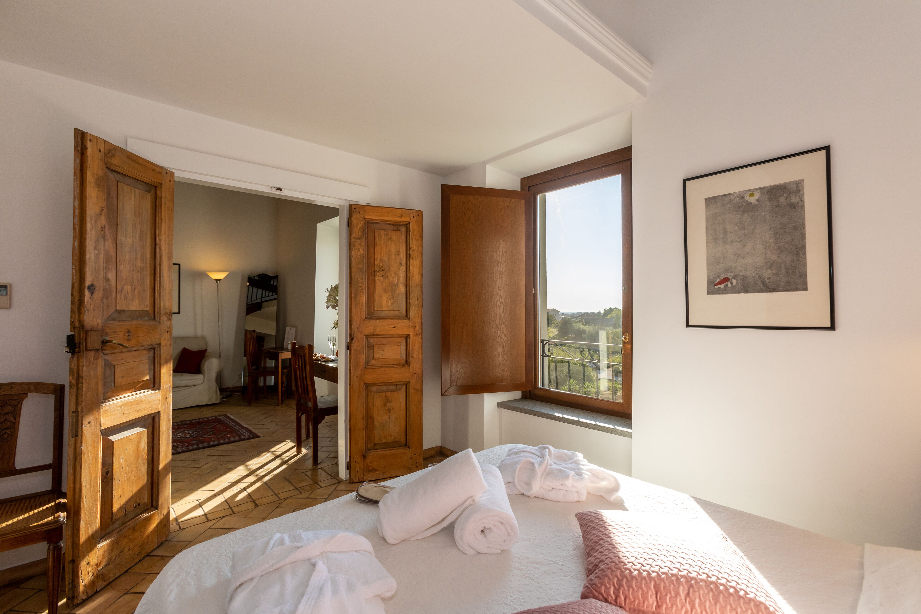 Ein Hotelzimmer mit Bett, Handtüchern, einem Fenster mit Blick und einer Tür zu einem anderen Raum.