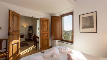 Ein Hotelzimmer mit Bett, Handtüchern, einem Fenster mit Blick und einer Tür zu einem anderen Raum.