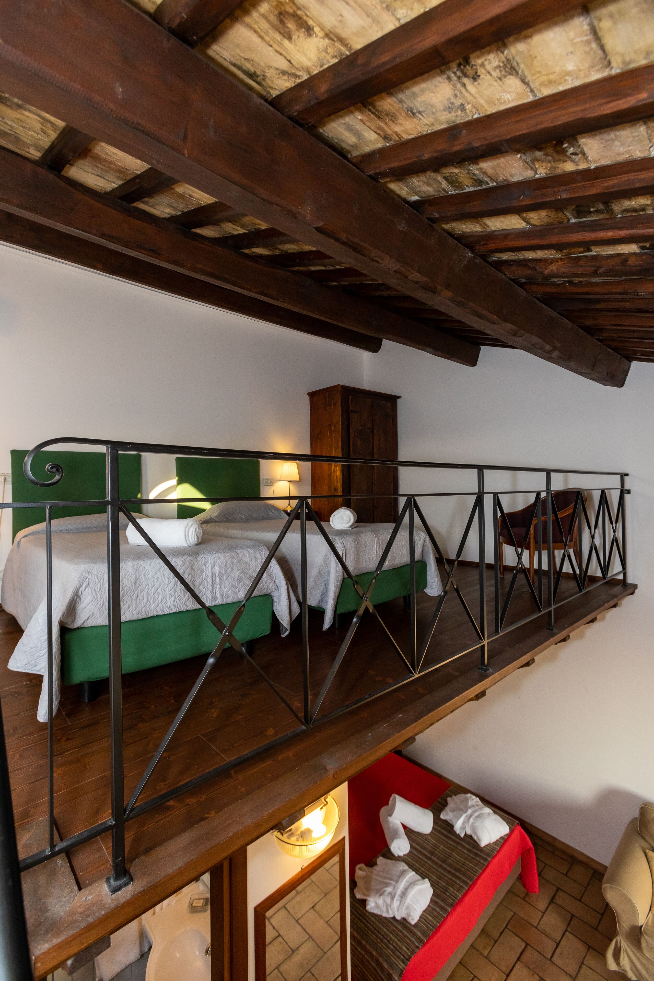 Un dormitorio estilo loft con una cama litera, techo de madera, una mesita con lámpara y una silla.