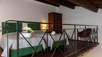 Un dormitorio estilo loft con una cama litera, techo de madera, una mesita con lámpara y una silla.