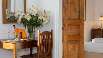 Uma mesa de madeira com um vaso de flores, uma cadeira e uma cama com porta de madeira.