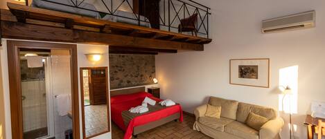 A cozy room with a loft bed, a sofa, a small table, and a mirror.