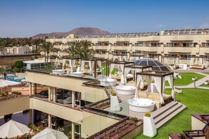 Een hotel dak met verschillende zitgedeeltes buiten, een zwembad en uitzicht op een bergketen.