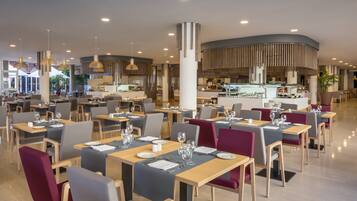 A modern restaurant with multiple dining areas, each with tables set for two.