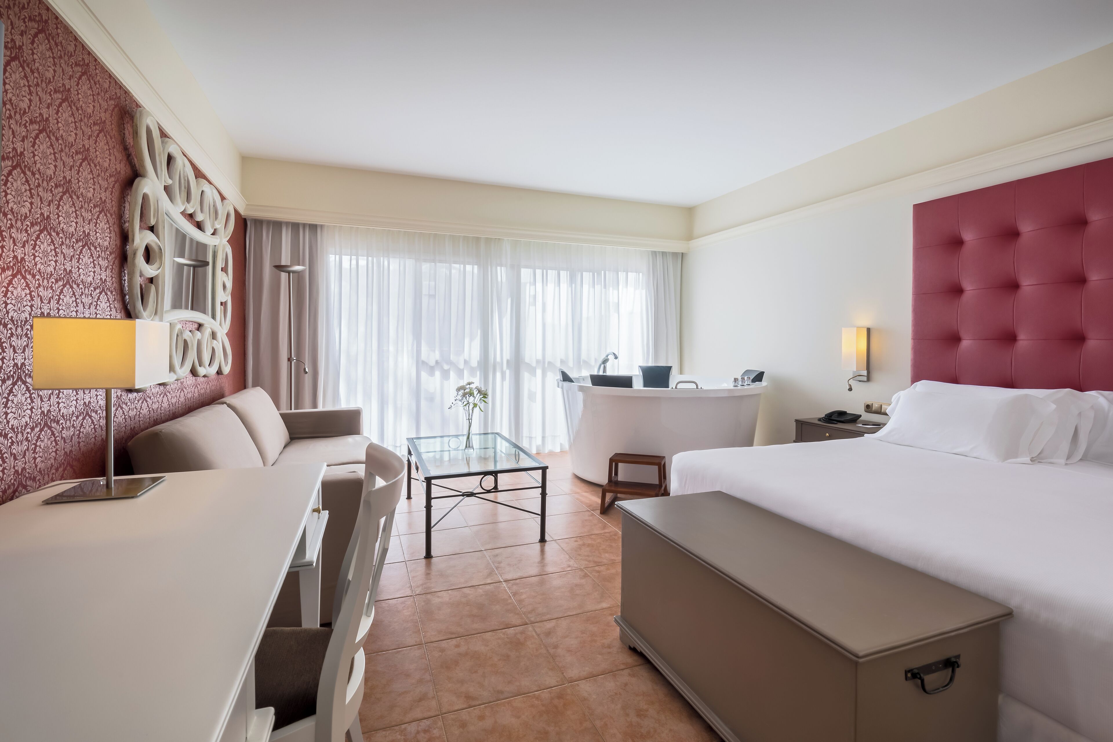 Una habitación de hotel con una cama, un escritorio, una silla, una mesita y un sofá.